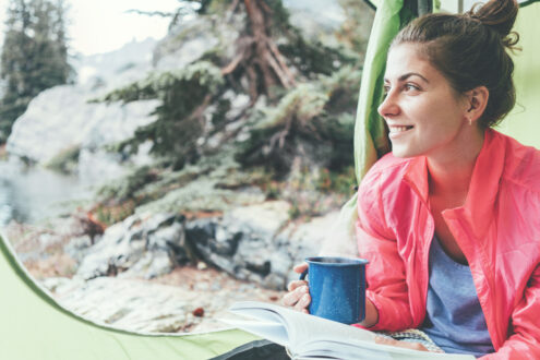 Kobieta czyta książkę pod namiotem